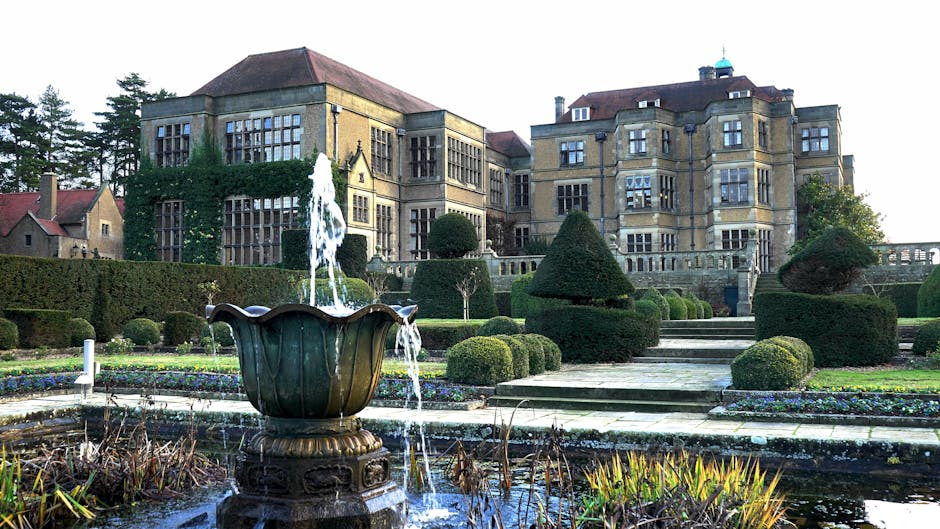 A well-maintained garden scene featuring neatly trimmed, rounded bushes and small conifer trees with dense, dark green foliage. The lawn area has fresh, evenly cut grass with a smooth, vibrant surface